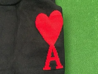 Framed source view of the red heart and letter design on black knit fabric