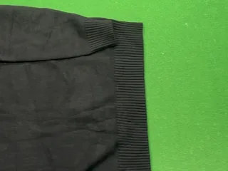 Framed view of the ribbed cuff and adjacent black knit panel from the front photograph
